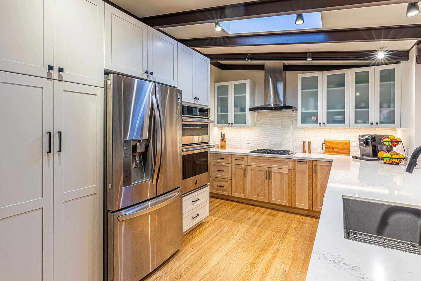 A modern kitchen with stainless steel appliances, white cabinets, and a large island in the center.