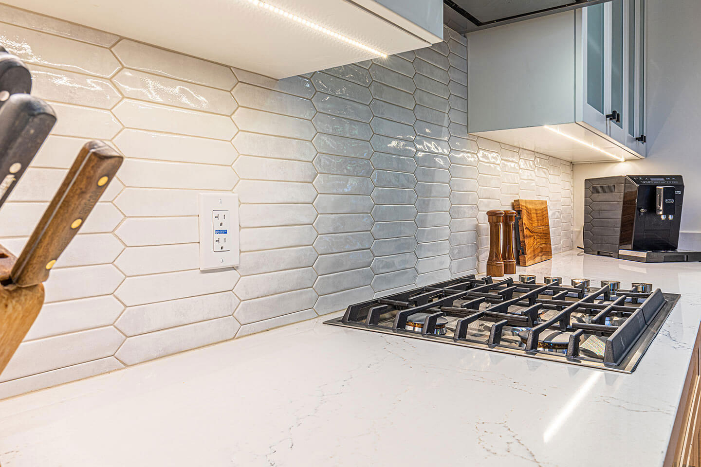 An ultra-modern kitchen with a large island and high-end appliances, featuring a sleek tile backsplash and stainless steel fixtures.