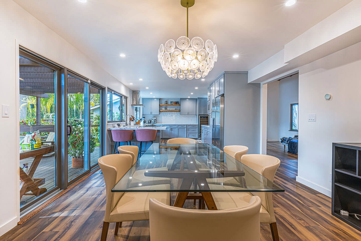 A modern living room with hardwood flooring, contemporary furniture, and a chandelier.
