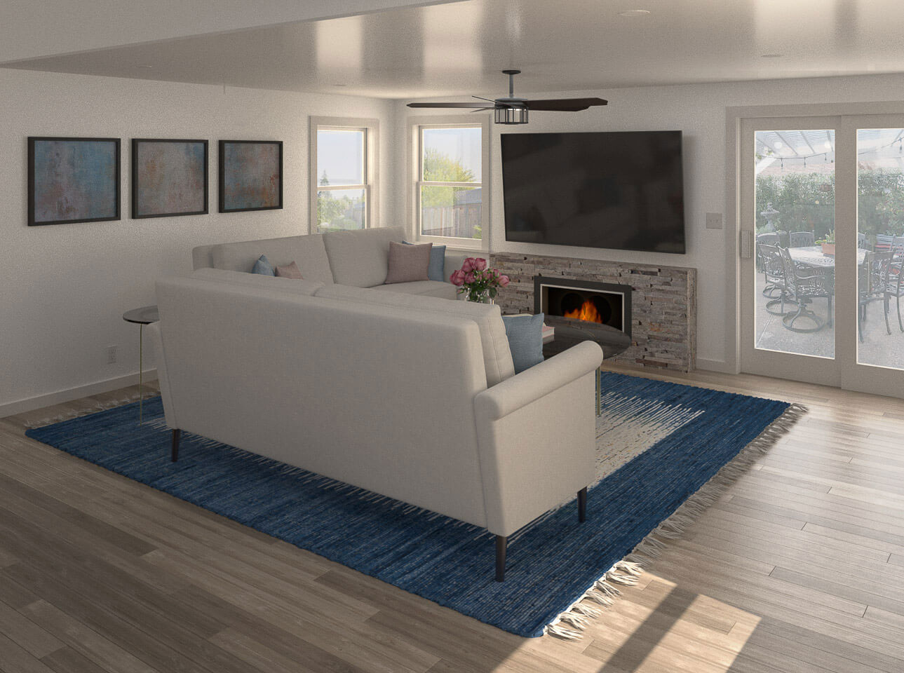 A modern living room with a white couch, blue area rug, open floor plan, a fireplace, and large windows allowing natural light to fill the space.