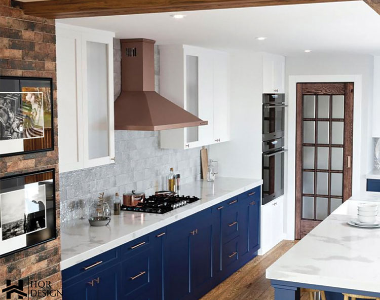 The image features a modern kitchen with blue cabinets, stainless steel appliances, a marble countertop, and a brick wall with a hanging picture.