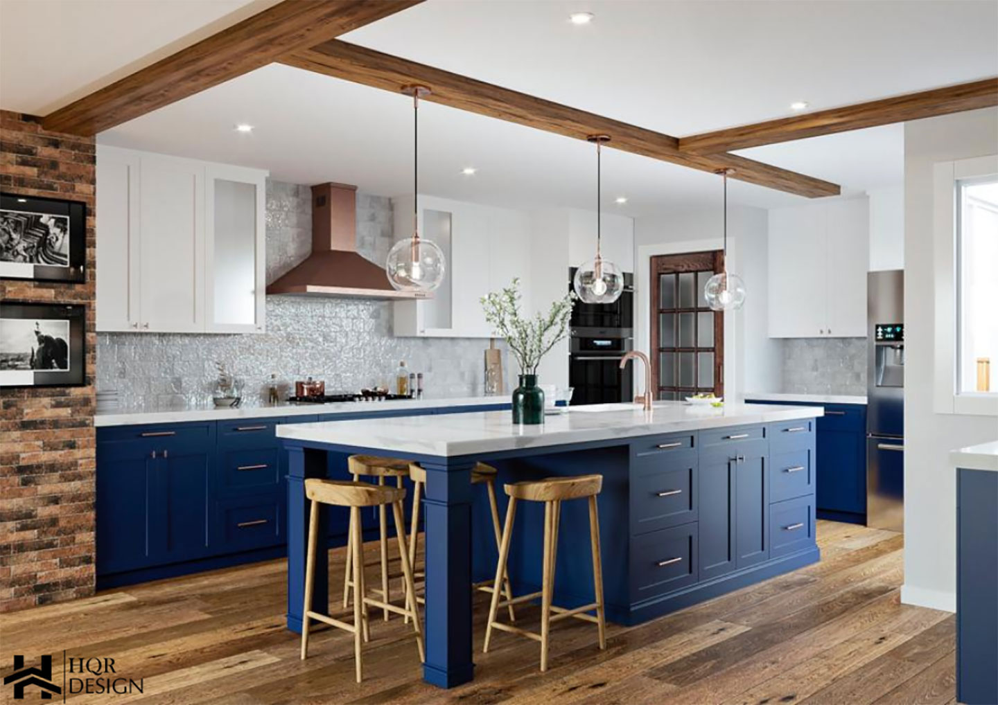 A modern kitchen with blue cabinetry, white countertops, and stainless steel appliances, featuring a brick wall and an island with bar stools.