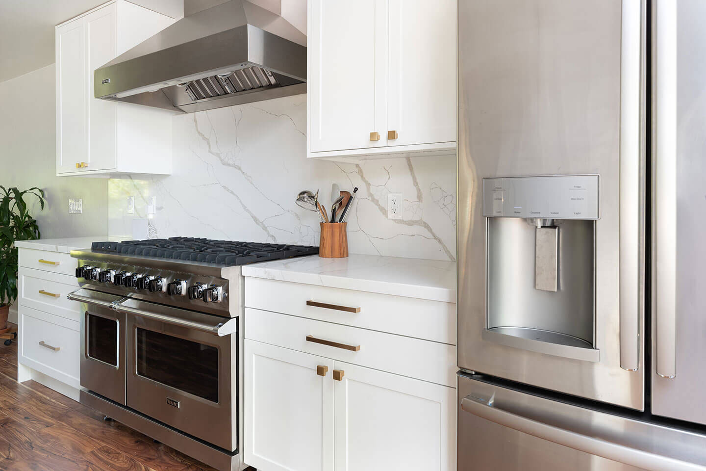 A modern kitchen with a large island, stainless steel appliances, white cabinets, marble countertops, and a built-in coffee maker.