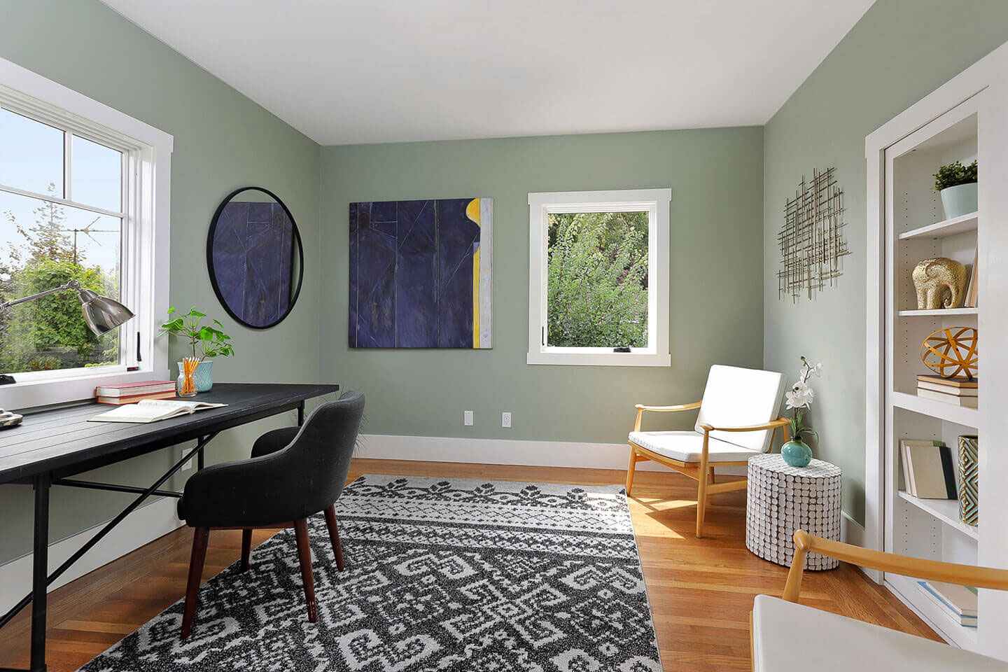 The image depicts a well-lit room with a modern design featuring a desk, chair, rug, window, and various decorative items.